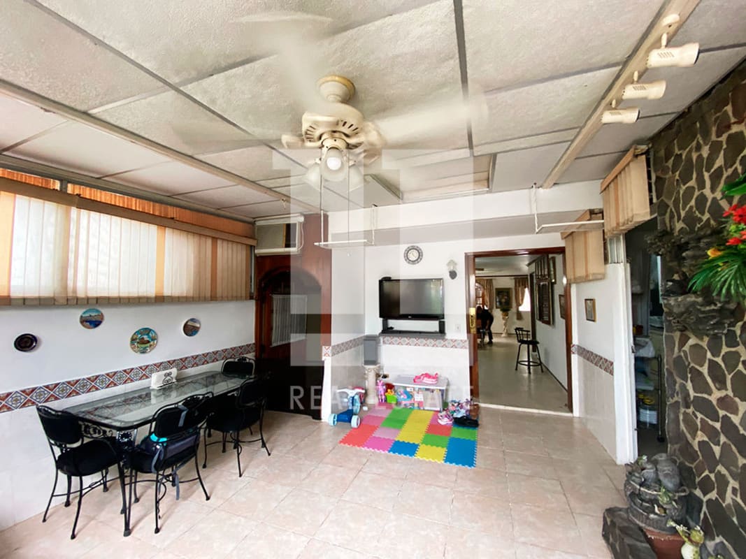 Living dining room with ceiling fan, glass dining table, stone accent wall in Panama home