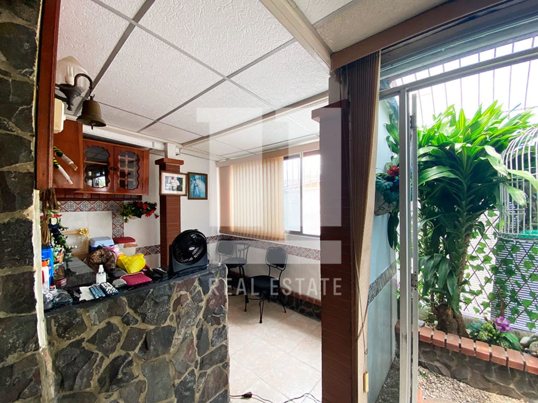 Kitchen dining area with wood cabinets, stone counter, sliding door to garden Panama home