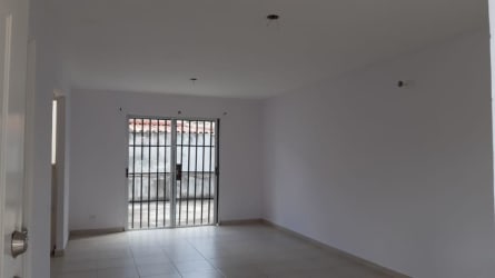 Empty living room area with sliding glass doors opening to patio in Villas de Aragón house Panama
