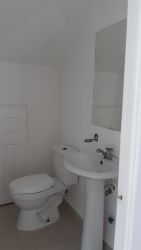 Compact bathroom with pedestal sink and wall mirror in Villas de Aragón house Arraiján Panama