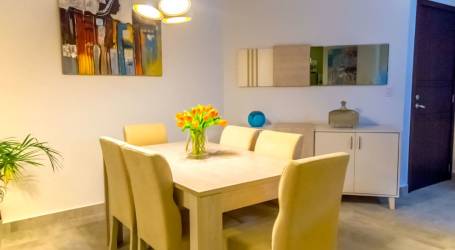 White cabinetry kitchen with quartz counters, appliances and breakfast bar in Tucan Country Club Panama apartment