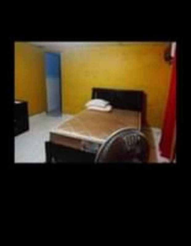 Basic bedroom with yellow walls double bed fan curtain affordable housing Panama La Siesta