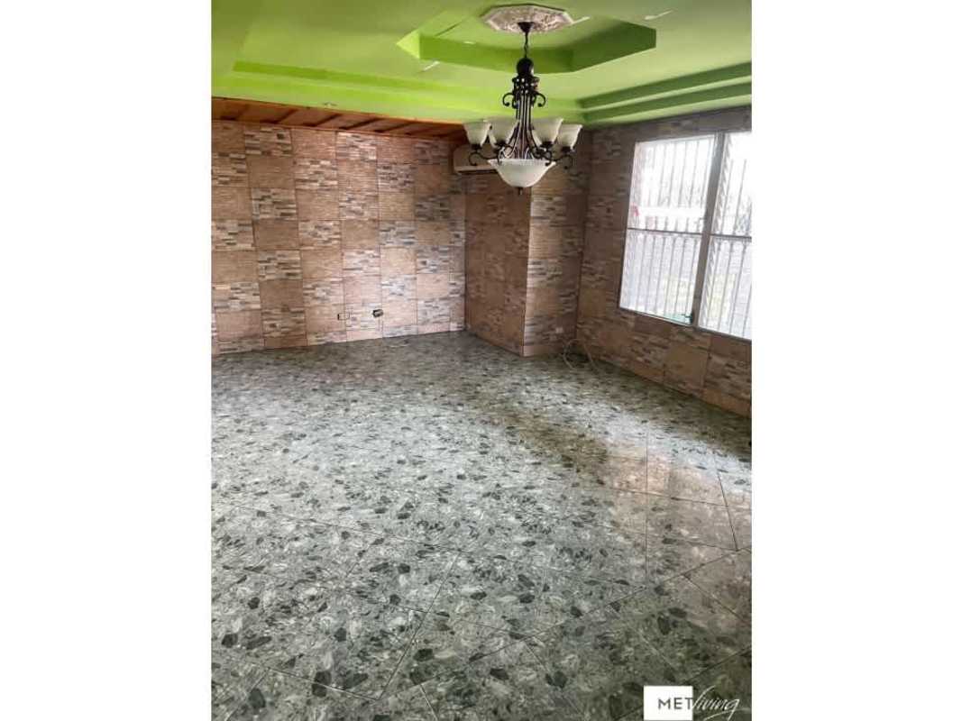 Living room with brick-pattern tiled walls, green painted tray ceiling and chandelier in San Miguelito house for sale