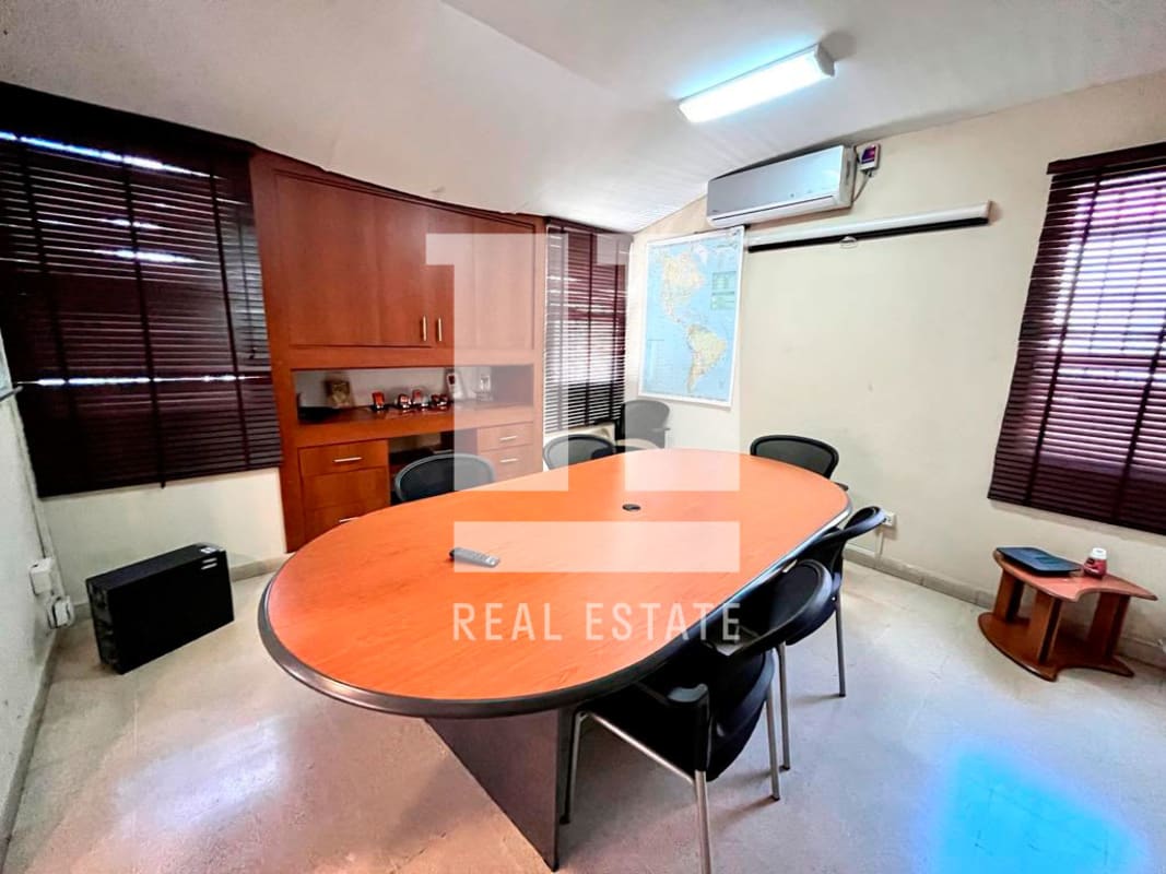 Commercial meeting space with oval table, built-in cabinets, world map decor Via Cincuentenario