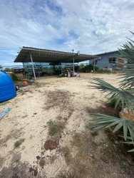 Basic one-story house, metal roof carport, blue water tank in Penonomé Coclé countryside