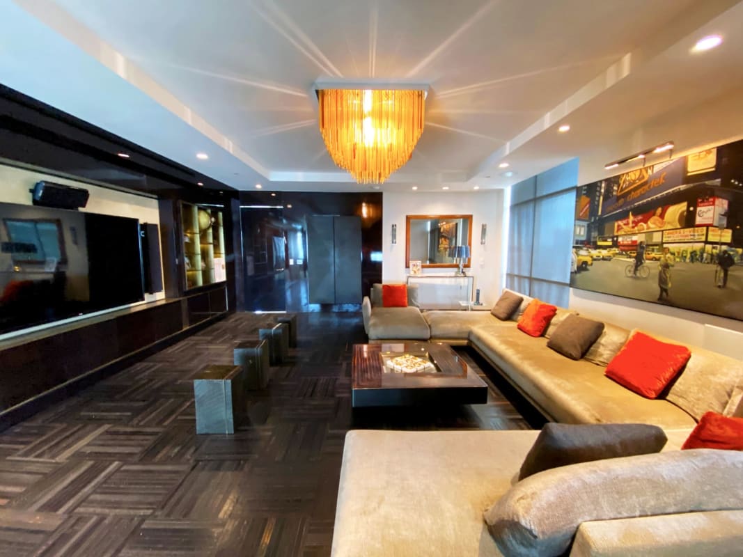 Modern dining area with glass table, black chairs, and chandelier in luxury penthouse Pacific Point Panama
