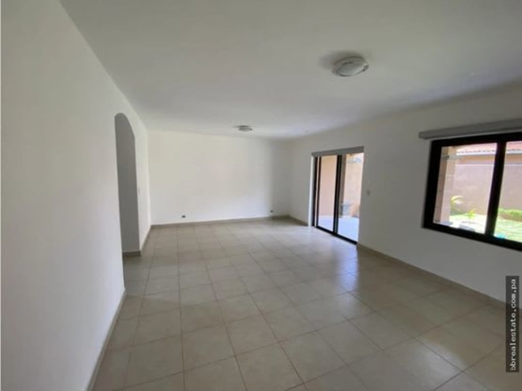 Empty living space with tiled floor and glass door to backyard in Panama house Versalles