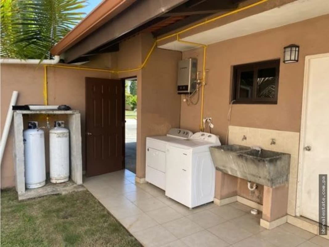 Covered laundry area with washer, utility sink, and storage in Versalles house Panama City