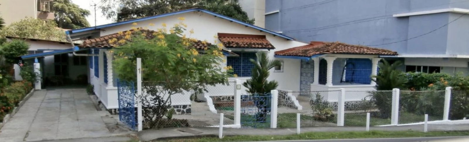 Gated commercial property with terracotta roof, blue trim, parking and garden on corner lot San Francisco Panama
