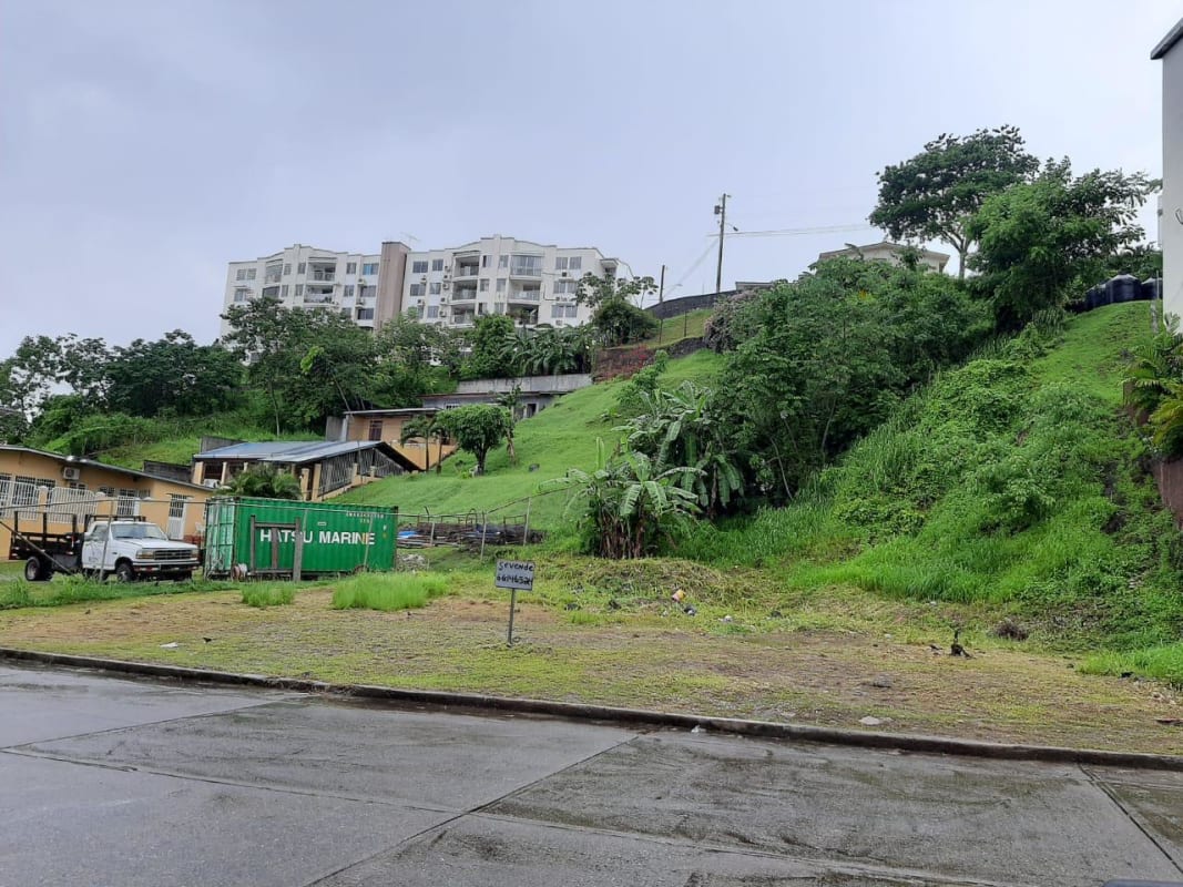 Elevated lot with grassy slope and nearby residential complex in Altos de Santa María, Panama City