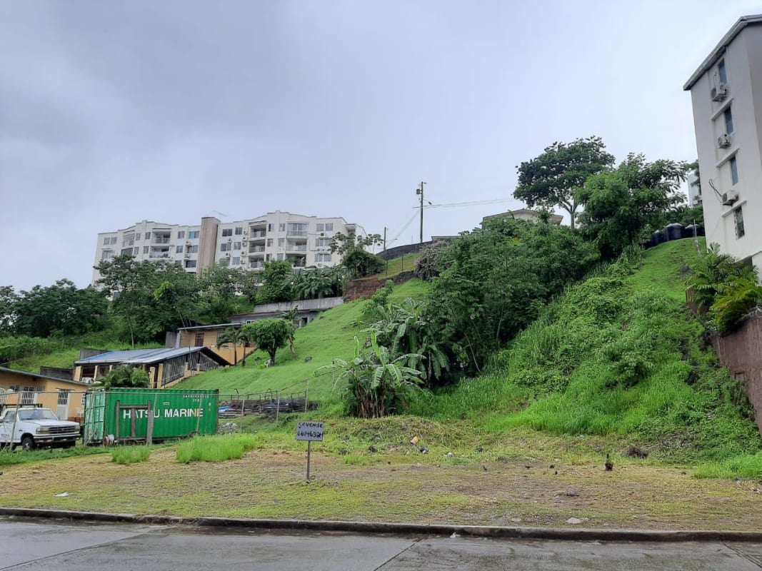 Vacant hillside property with container, greenery, and nearby apartments in San Miguelito Panama