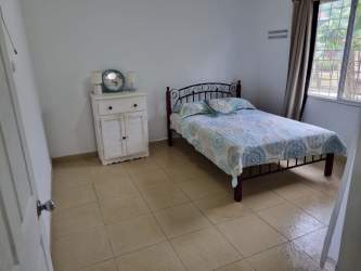 Minimalist bedroom with tiled floor, large window and nightstand in El Carate Panama