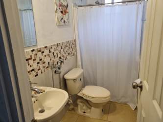 Modern bathroom with mosaic tile backsplash, white shower curtain, and ceramic sink in Las Tablas El Carate house