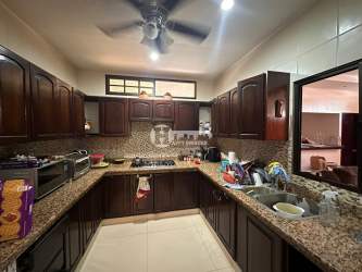 Kitchen with dark wood cabinets, granite countertops, mosaic backsplash and ceiling fan in La Villa de Los Santos house
