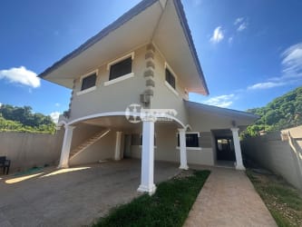 Exterior of elevated two-story house with arched portico, garden and covered parking in La Villa de Los Santos