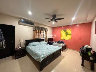 Large bedroom with king bed, red accent wall, AC and ceiling fan in La Villa de Los Santos house