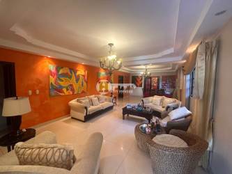 Living area with orange accent wall, bright windows, sofas and art in La Villa de Los Santos rental house