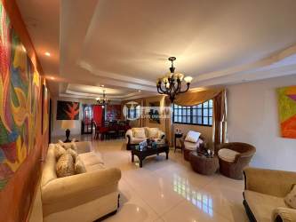 Spacious living room and dining area with chandeliers, ceramic floors and colorful art in La Villa de Los Santos rental