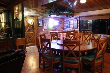 Large rustic dining area brick walls wood ceiling chandelier Chame Panama estate