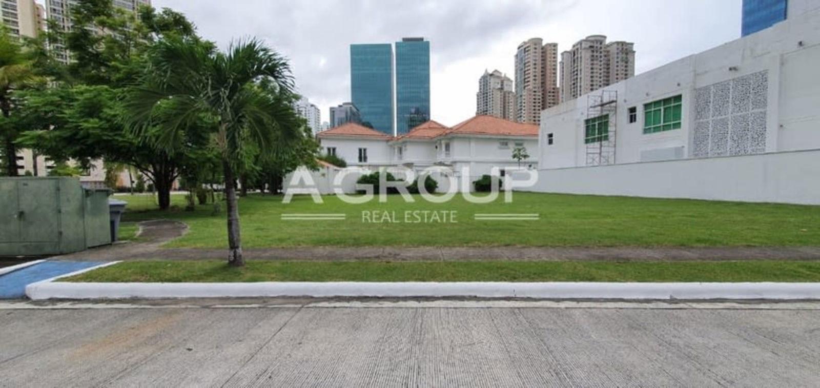Open residential lot with green lawn, palm trees, and modern towers nearby in Gold Point Punta Pacífica Panama