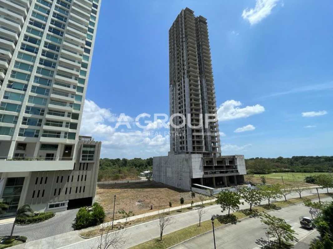 Modern glass facade towers under construction next to open land Santa María Panama