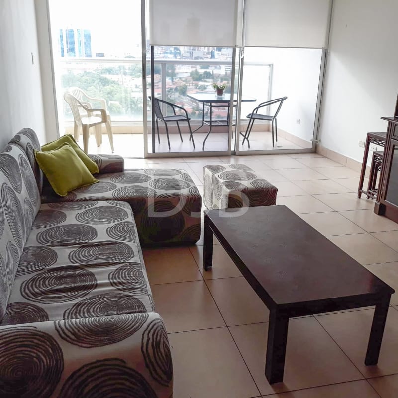 Living room with patterned sofa, large windows opening to balcony with city views PH San Francisco Tower Panama City