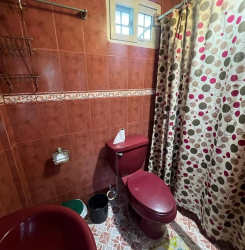 Mediterranean style house with covered porch, red tiled roof, lush garden at Playa Costa Esmeralda San Carlos Panama