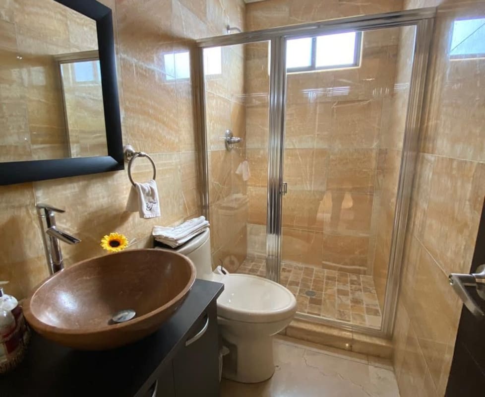 Bathroom with glass shower, stone vessel sink, marble tiles in El Carmen Obarrio house