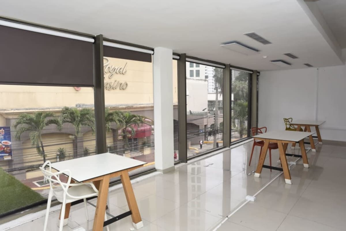 Bright open workspace with colorful chairs, tile floors, city street view Panama financial district