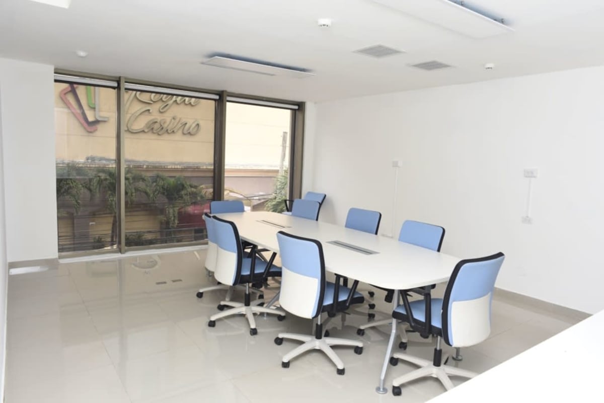 Large modern conference space with glass wall, white table, blue chairs overlooking city Panama