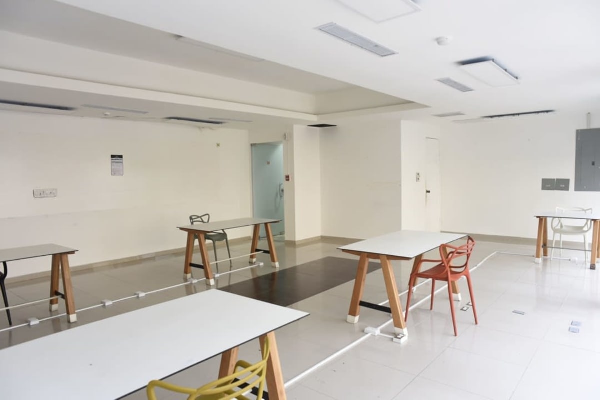 Open shared workspace with white desks, colorful chairs, tile floors Panama City commercial rental