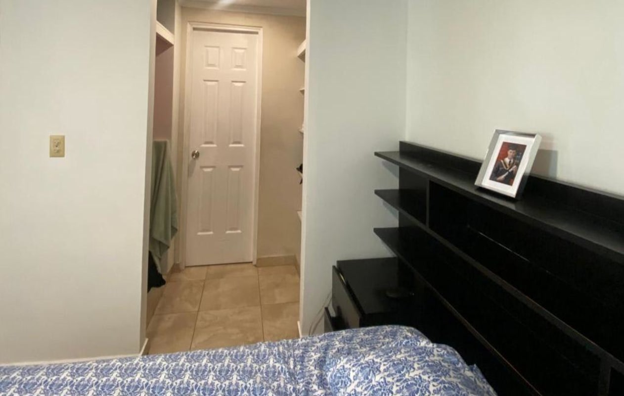 Bedroom with blue bedspread, open shelving, white door, tiled floor in PH Girasol PL