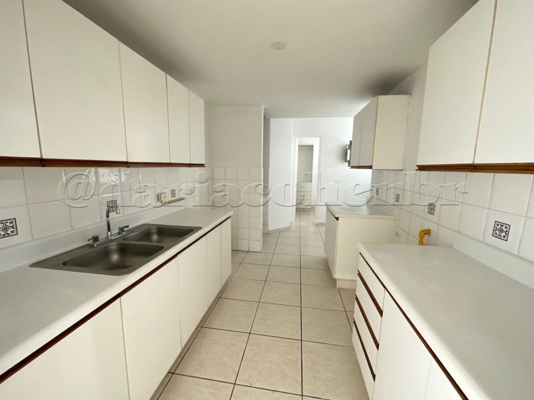 Bright galley kitchen with white cabinets and tile floors apartment PH Coco Mar Panama