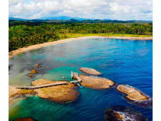Aerial photo of beachfront lot with sandy beach, rock shoreline, private dock potential and dense greenery at Villa Real Bay, Colon