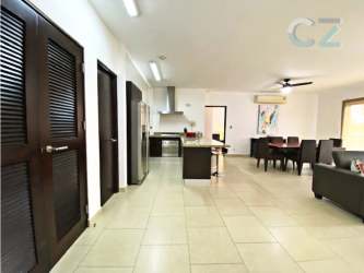 Open-plan living dining space with modern black sofas, red chair, ceiling fans in PH Soleo Panama Pacifico
