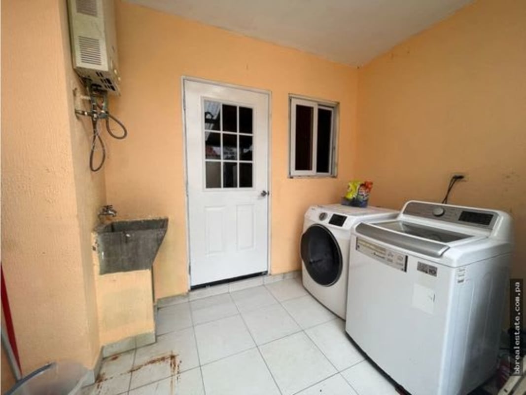 Laundry area with utility sink, washer hookup, and peach walls in Panama house