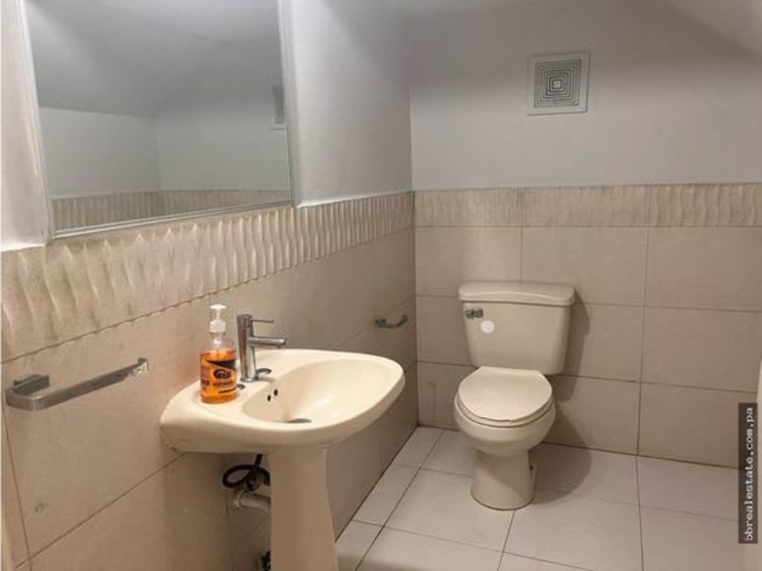 Beige-tiled bathroom with mirror, pedestal sink, and fixtures in Quintas de Versalles Panama