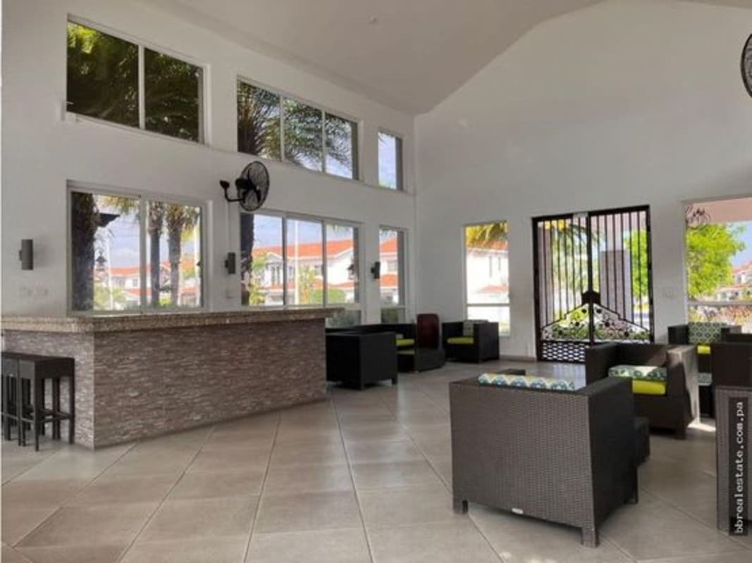 Community clubhouse lounge with high ceilings, bar, wicker seating and large windows at Quintas de Versalles