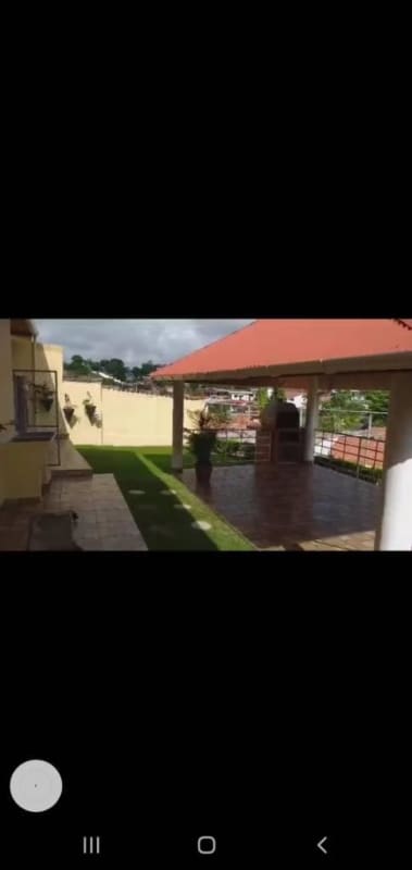 Covered gazebo with red roof, barbecue grill, tiled patio and garden in Alto del Bosque house Panama