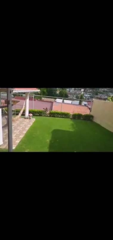 Outdoor covered patio with hammock, tiled floor, city view, and lawn Alto del Bosque house Panama