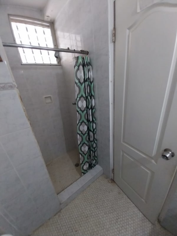 Tiled bathroom with shower area and pedestal sink in duplex Pedregal Panama
