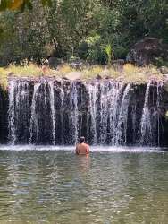 Person swimming near a natural waterfall with greenery El Chirú Coclé