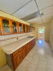 Galley kitchen with wood cabinets and tiled counters in Fuente del Chase home La Chorrera Panama