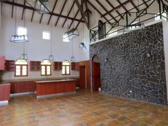 Luxury bathroom with double vanity, large mirror, arched window, and bathtub in mountain villa