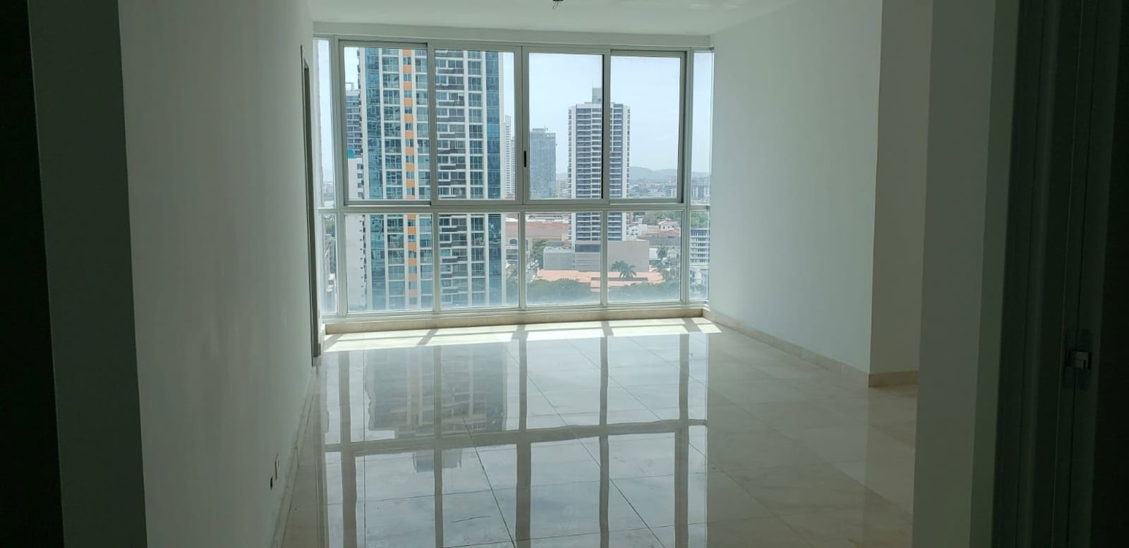 Modern living room with marble floors, large glass doors to ocean-view balcony PH Bella Vista SkyTower Panama