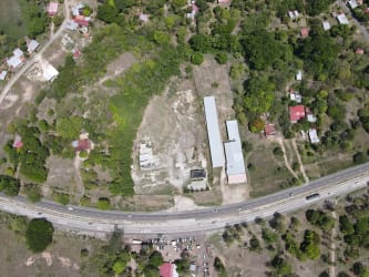 Aerial showing large land parcel with warehouse, green terrain, adjacent to road in Penonomé Coclé Panama