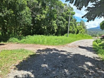 Gravel country road through wooded green lot with sunny mountain backdrop in Boquete Panama
