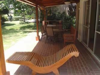 Covered brick patio with outdoor dining overlooking tropical garden in Playa Blanca villa