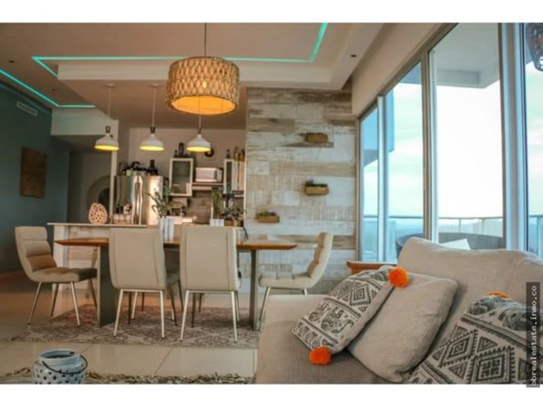 Modern condo kitchen, island seating, large windows with ocean skyline view.