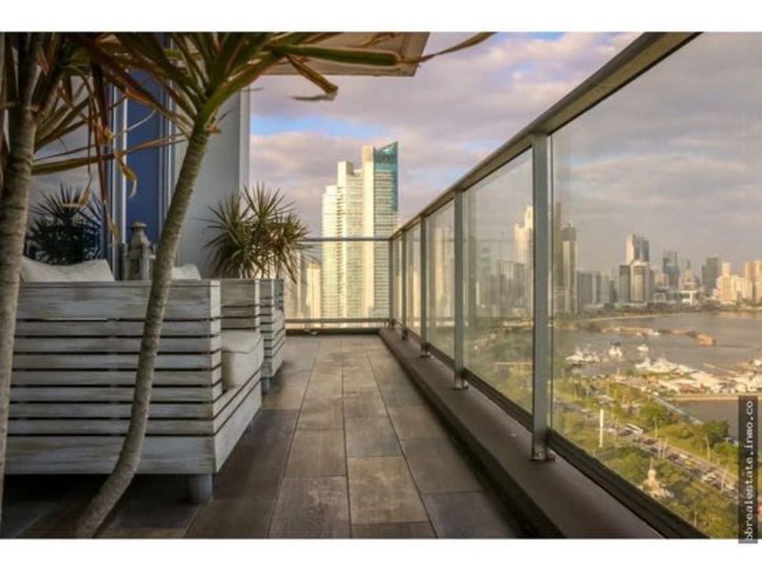 Wide terrace with seating overlooking the ocean and modern skyscrapers in Panama City.
